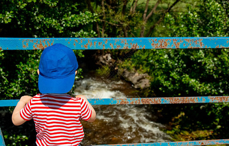 小孩子站在山河边的桥图片