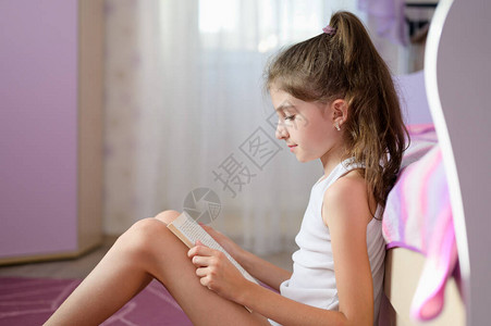 女孩坐在床边看书的家里在上拿着一图片