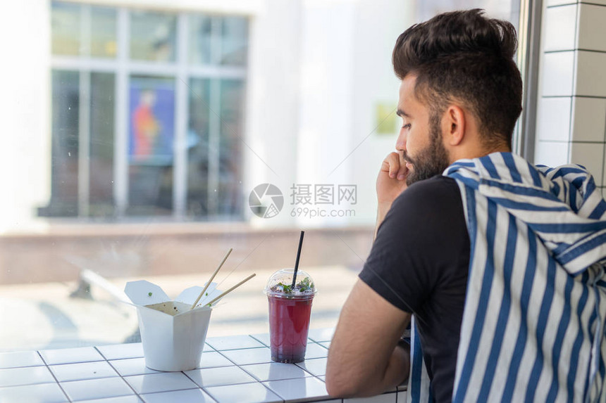 一个英俊的阿拉伯男子在咖啡馆喝冰淇淋的肖像休息图片