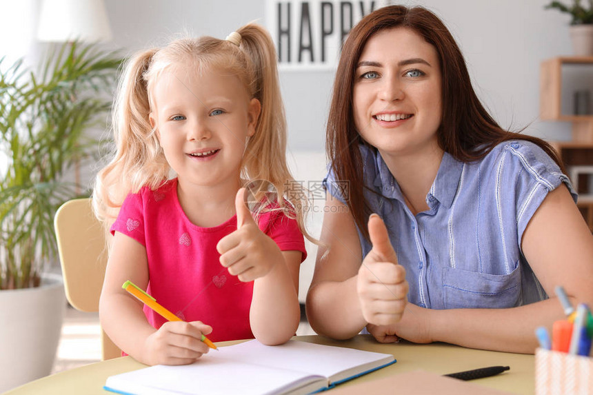 母亲帮助她的小女儿在家上课图片