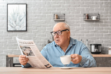 家中阅读报纸时喝茶的老人肖像在图片