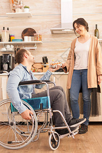 坐在轮椅上的残疾人在厨房里为妻子拿着鸡蛋盒残疾瘫痪残疾人在事故后图片