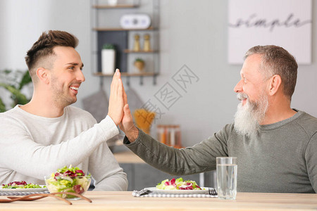 老人和他成年的儿子在厨房吃饭图片