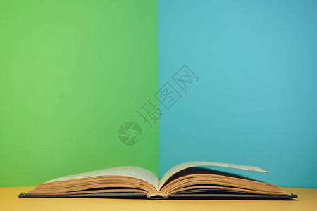 新书黄桌和蓝色绿墙背景的美丽开放书背景