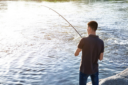 年轻人在河里钓鱼图片
