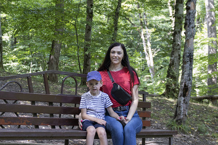 妈在夏末家庭假期在公园里休息母亲和儿子坐在城市公园的长椅上一起幸福母图片