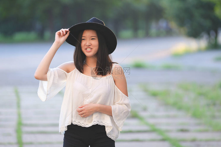 女天保持他的帽子夏天太阳日落看起来很高兴azitka女人黑色头发白色衬衫黑色短裤看着相机在树周围跳舞图片