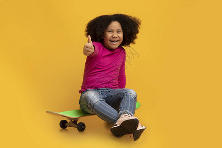 快乐的黑人小女孩坐在滑板上图片