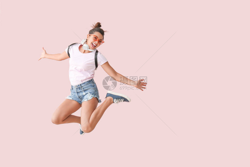 带着耳机在彩色背景上跳跃的女人图片