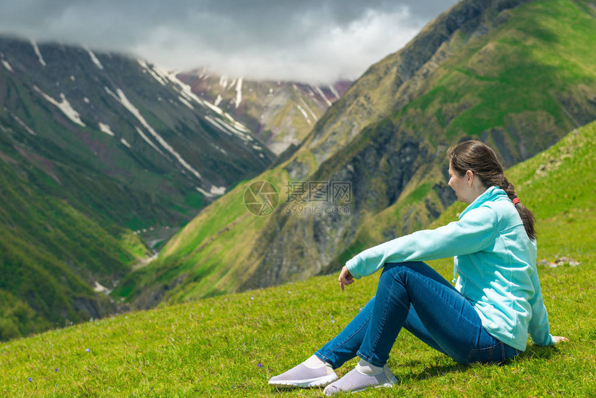 一位女士坐在草地上崇拜高加索美丽的山地图片