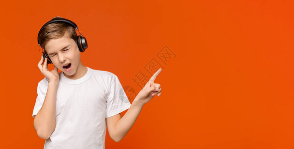 年轻的音乐情人青少年男孩在无线耳机橙色全景背和空间上享图片