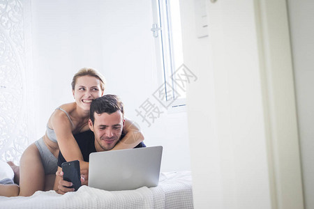 幸福的年轻美女情侣在家中玩耍活动在白床图片
