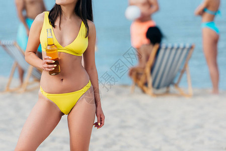 穿着泳衣的年轻女子在沙滩上站着时图片