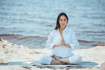 身穿anjaliMudra盐海豹在海边瑜伽垫上摆姿势的年图片