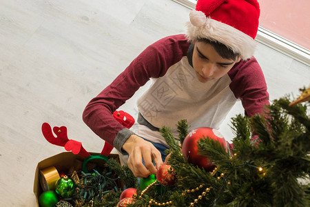 男孩在家装饰圣诞树的特写图片