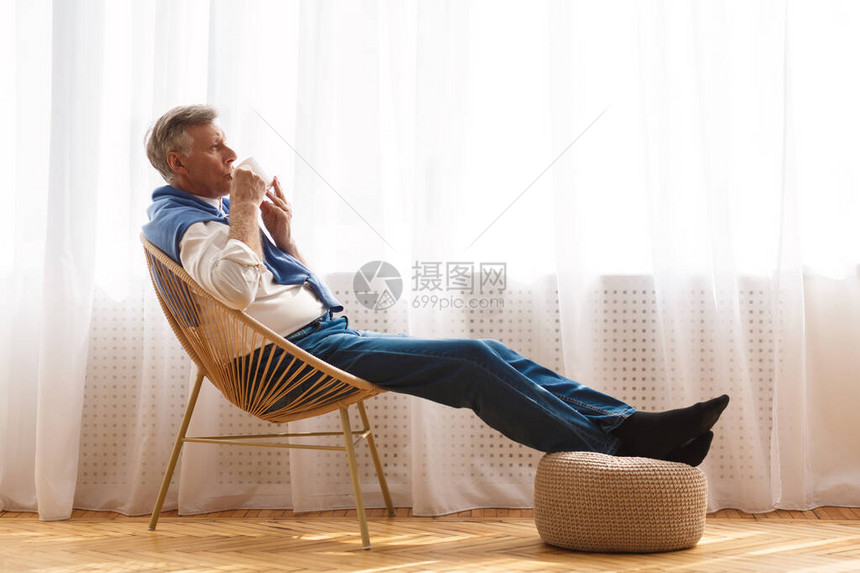 休闲老人享受清晨咖啡在窗户旁边的椅子上喝着咖啡侧图片
