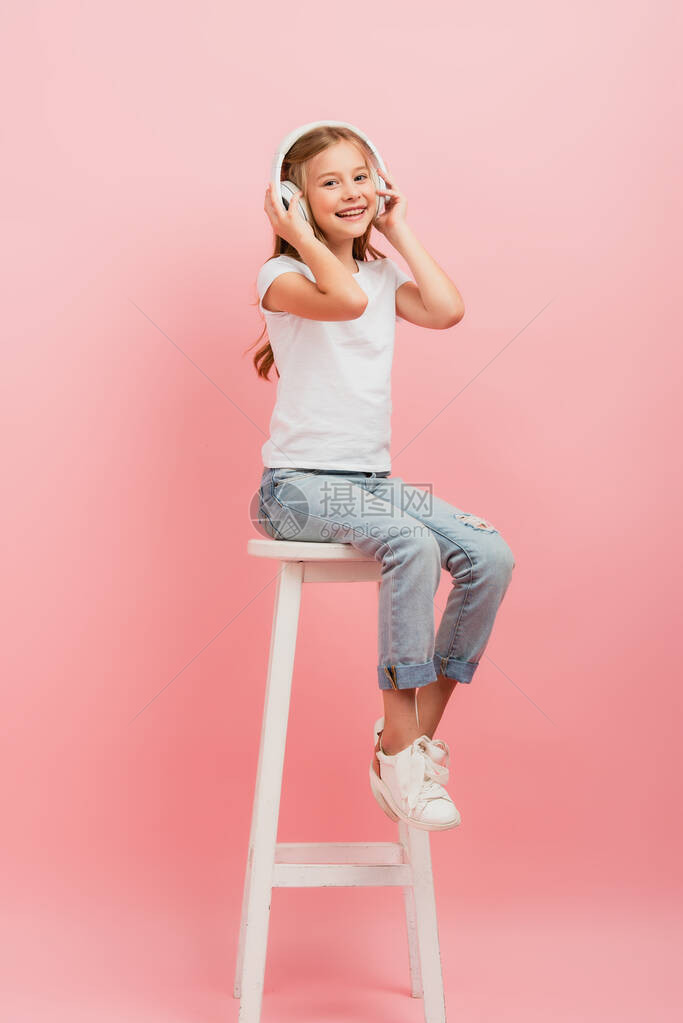 穿着白色T恤衫和牛仔裤的女孩坐在粉红色高凳上时图片