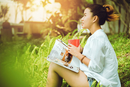 亚裔女人坐着放松看杂志和喝咖图片