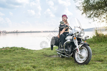 美丽的女人与头盔和摩托车合影图片