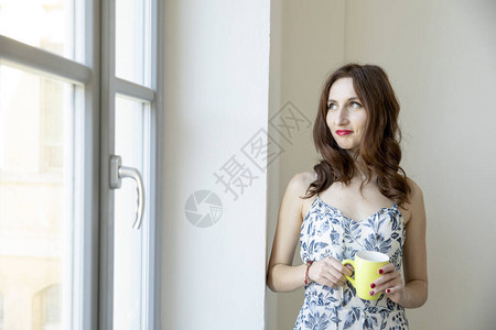 长头发的白发女孩向窗外看喝着黄图片