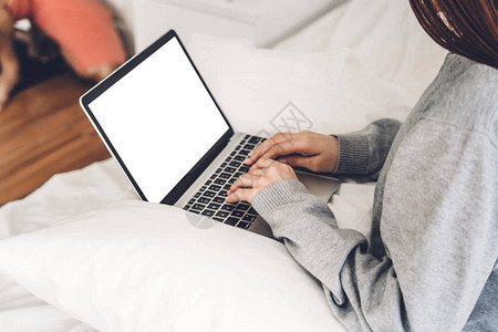 年轻女在卧室里使用笔记本电脑放松身心女检查社交应用程序和工作通图片