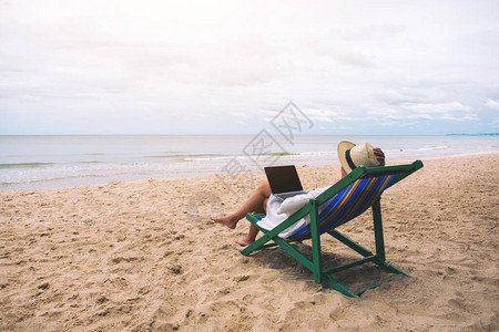 一个女人躺在沙滩椅上时在笔记本电脑图片