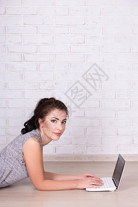互联网和社交媒体概念对躺在地板上在家里使用笔记本电脑的年轻美图片