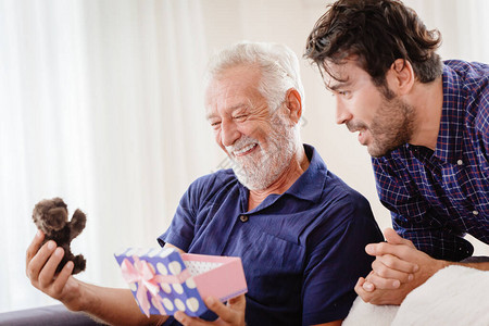 儿子在圣诞节假期给他的祖父送可爱的泰迪礼品盒时微笑着图片