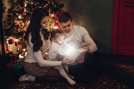 母亲父亲和小女儿为圣诞节打开魔法礼物图片