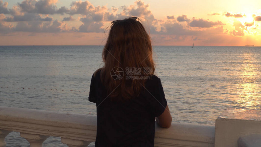 日落时站在海景背上的年轻女子的背影媒体有魅力的女人站在路堤上图片