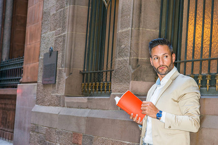 年轻的欧洲男子在纽约曼哈顿外面看红书图片