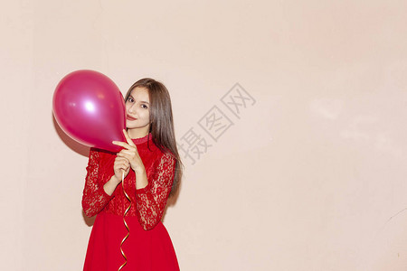 穿着红色衣服的年轻漂亮的女孩拿着气球情人节生日妇女节周年纪念日图片