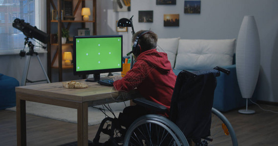 一个坐在轮椅上的男孩使用他的电脑的中景背景图片