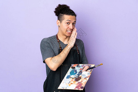 年轻艺术家手持调色盘在孤立的紫色背图片
