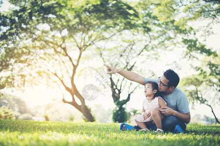 快乐的父亲和女儿用手指着看着公园里的东图片