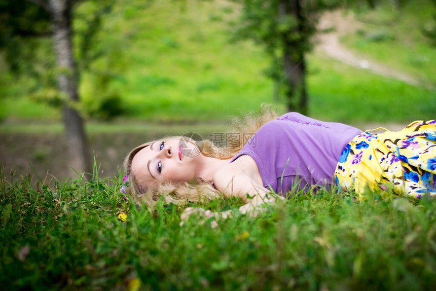 美丽的金发女孩躺在草地上微笑图片