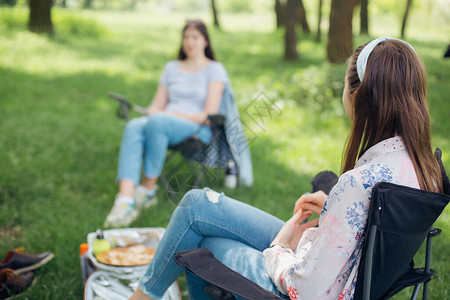 女孩之友在夏日公园内与社会距离相隔的野餐时图片