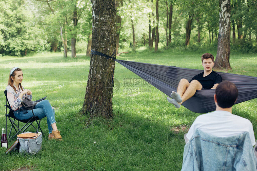 社交隔离一小群人在夏季公园的社交距离野餐中享受交谈朋友们在吊床上和树间的椅子上放松新世图片