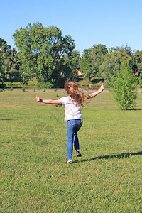 女孩跳上草坪幼稚的情绪快乐的孩子在夏天的草坪上玩得开心图片