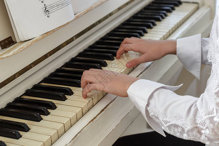 女孩在玩白色钢琴一个女孩的手按图片