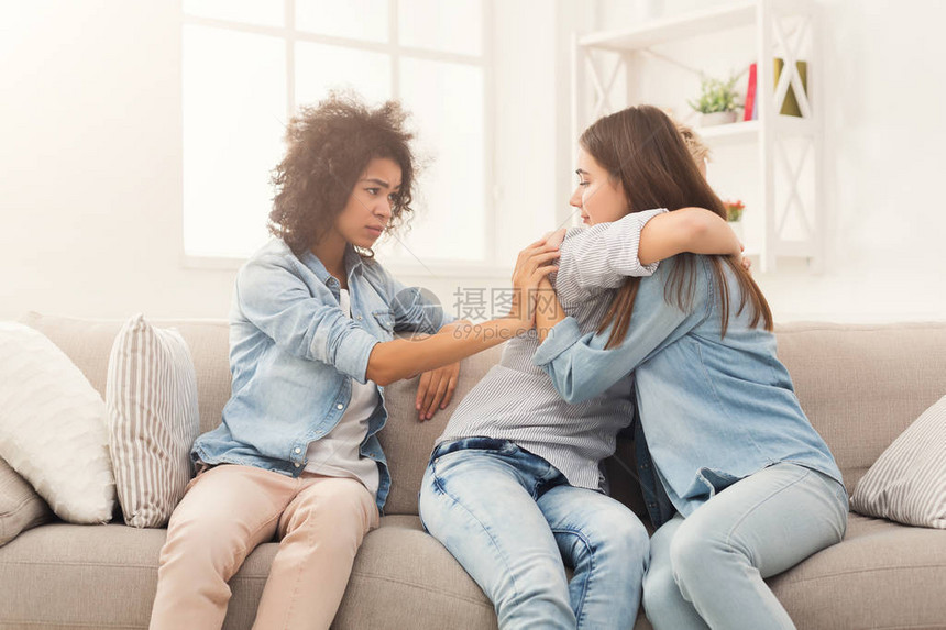 年轻女在谈论和安慰她们悲伤的朋友临时女孩在家里有共同的问题团结与支持的图片