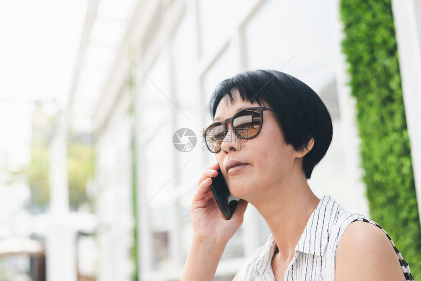 亚洲女人在户外坐着用手机说话图片