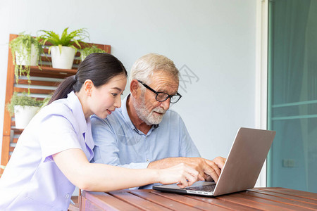 护士帮助在家用笔记本电脑工作的老年退休男子图片