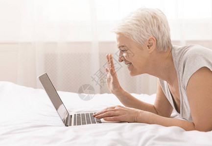 快乐的祖母在网上用笔记本电脑与亲戚交谈图片