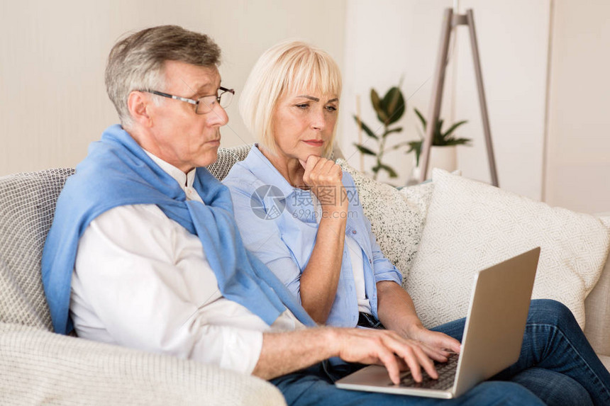 高龄夫妇在笔记本电脑上看新闻图片