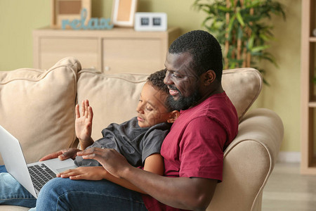 非裔美国人和他的小儿子在家里用笔记图片
