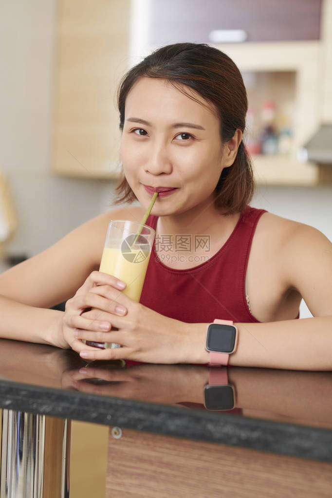 年轻微笑的亚洲女人的肖像喝着甜美味水果鸡尾酒图片