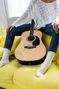 女人坐在沙发上拿着原声吉他的剪影图片
