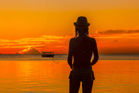 日落时站在沙滩上的女人图片