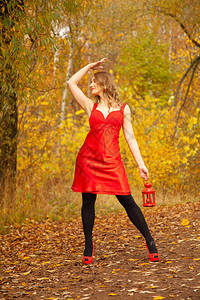 穿着红裙子的天主教女孩在秋天公园走来去带着古老的光芒在图片